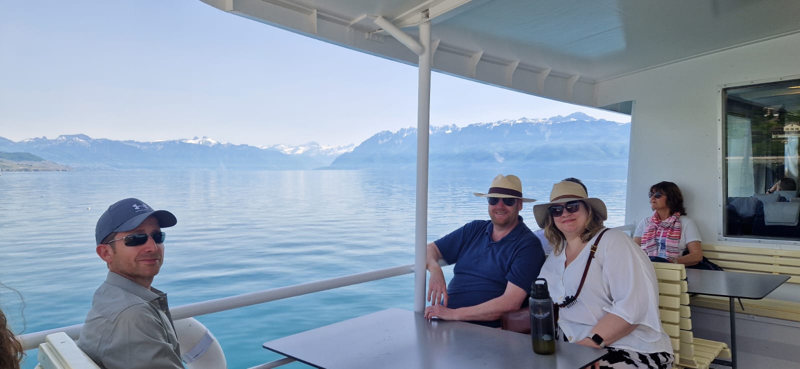 People enjoy a boat ride with a scenic view of water and snow-capped mountains in the background.