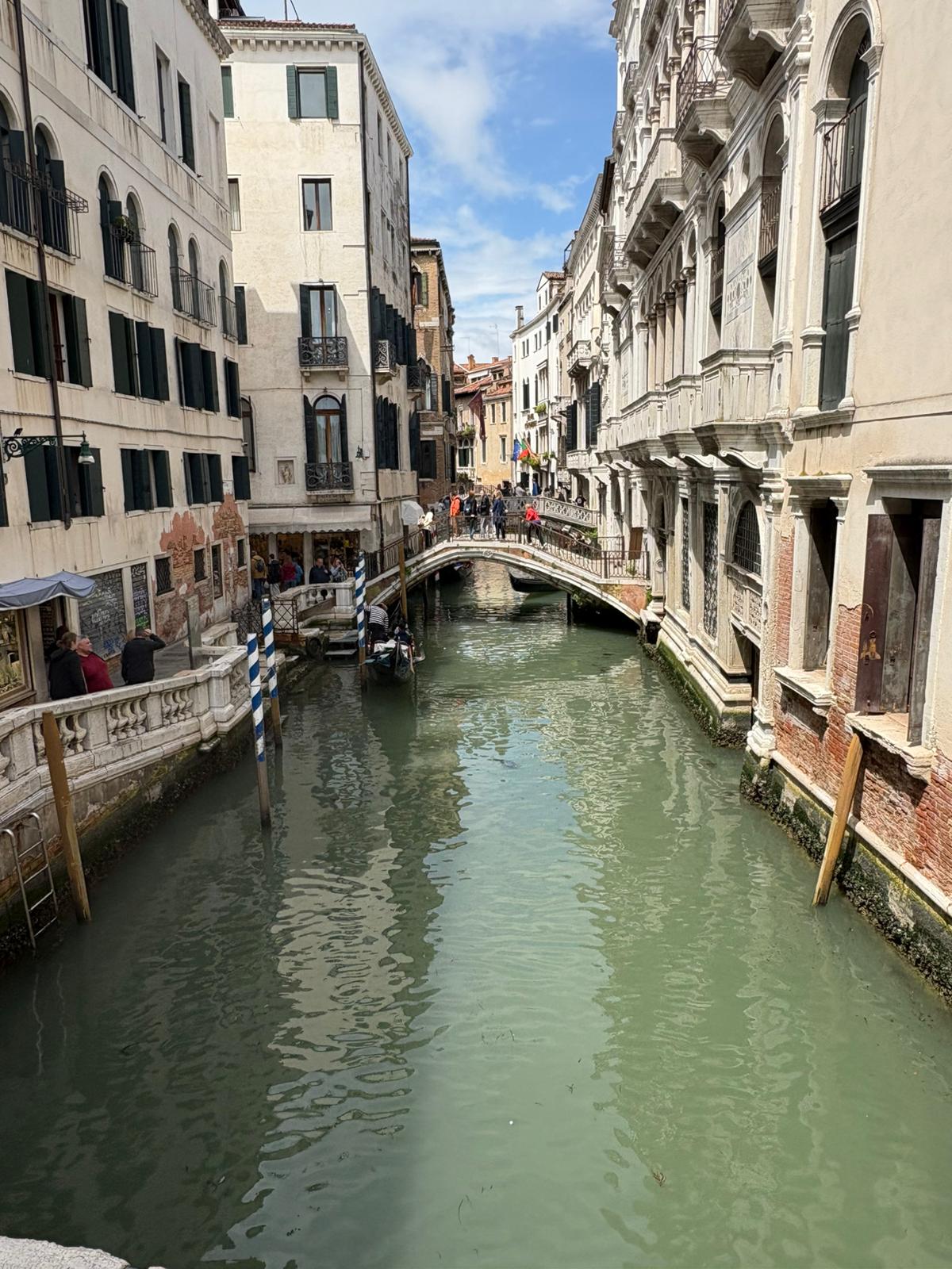 Venetian Canal and Stone Bridge Scene Narrow Venetian canal with stone bridge, flanked by old buildings and moored boats.
