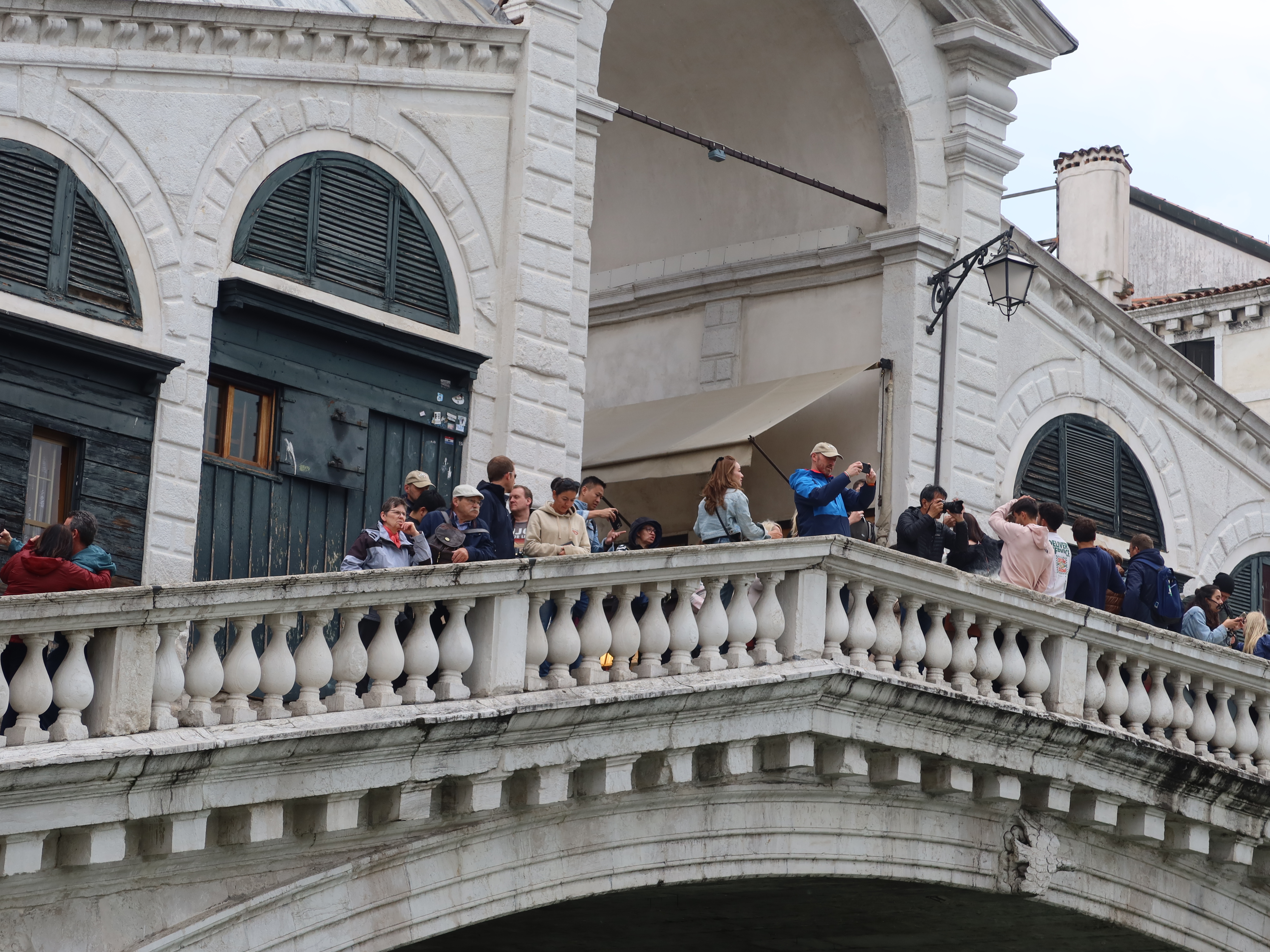 People on a historic stone bridge with arched windows and decorative railings.