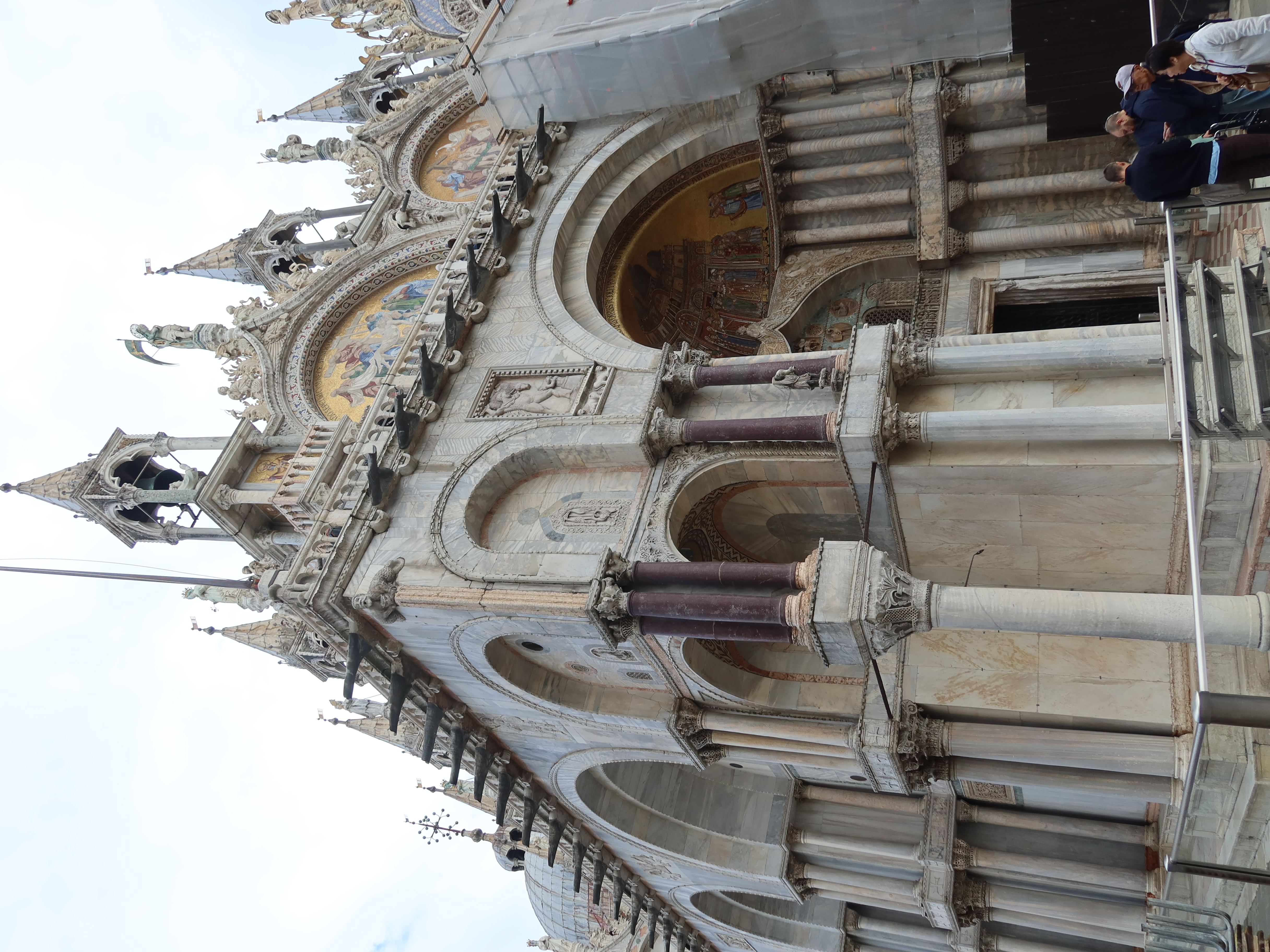 Historic Cathedral Facade with Ornate Architecture Historic cathedral section with ornate arches, columns, mosaics, spires, and nearby people.