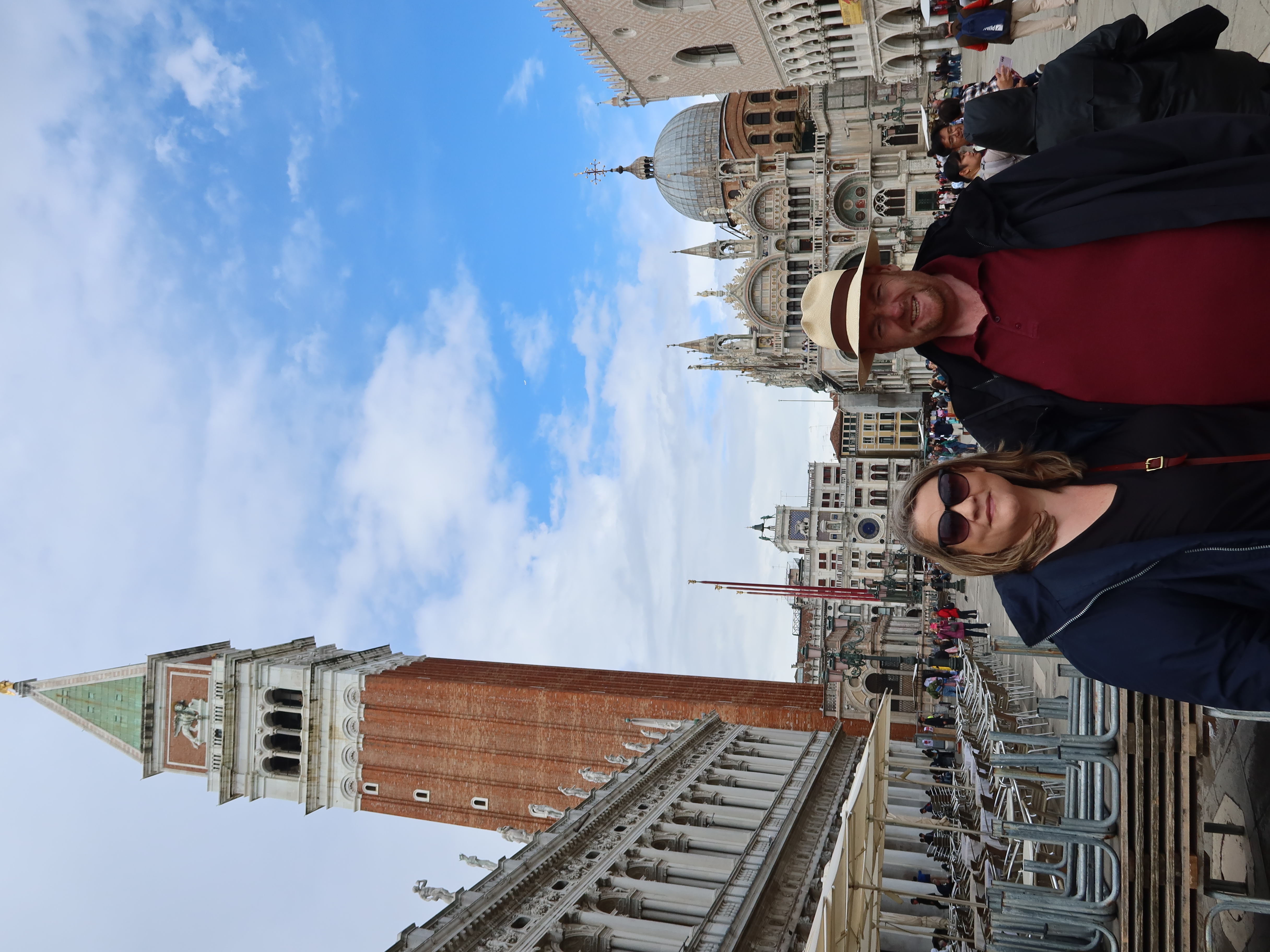 Couples Stroll in St. Mark’s Square Couple in St. Mark's Square, Venice, with Campanile and Basilica di San Marco in the background.