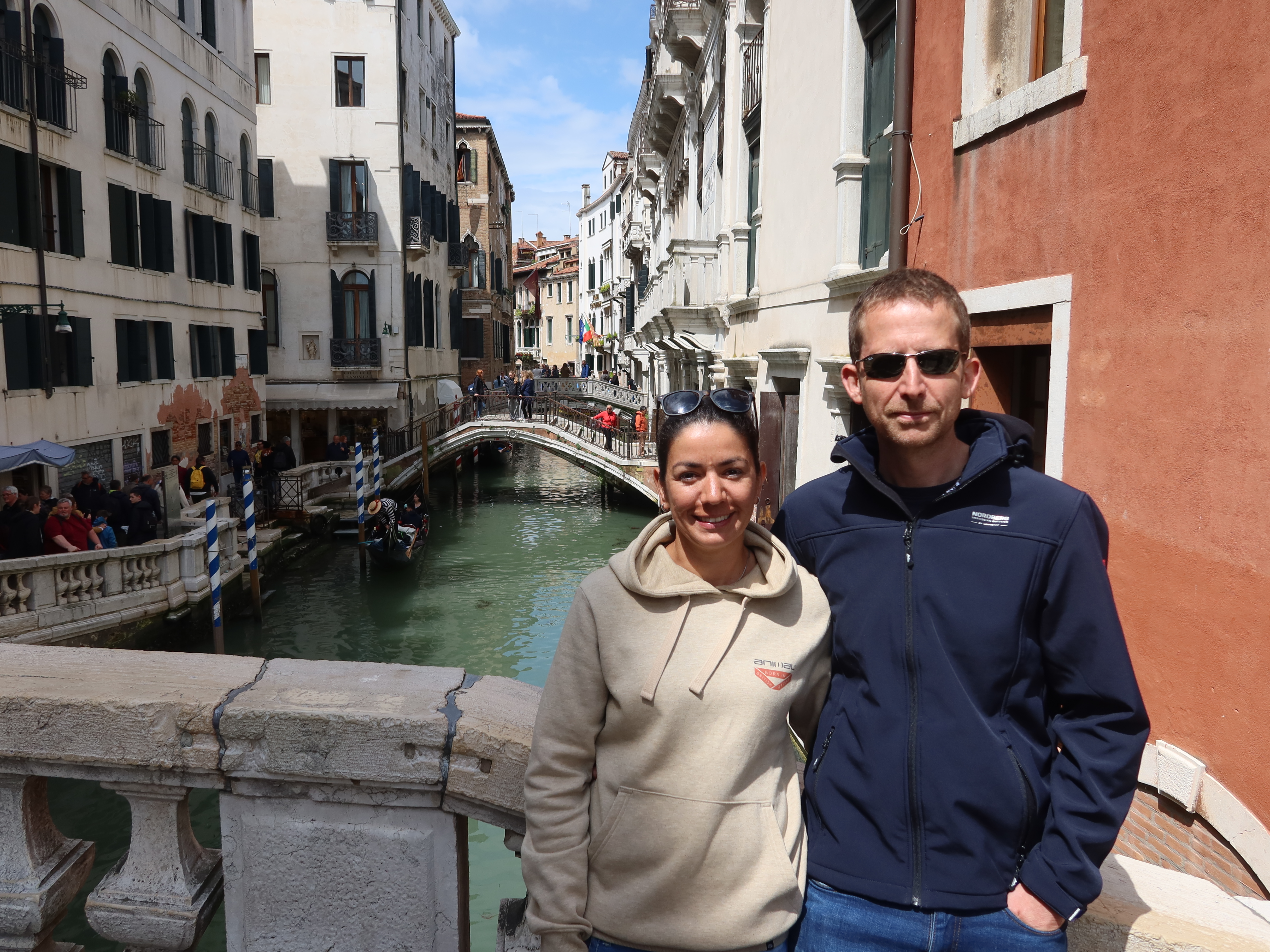 Canal Stroll on a Stone Bridge Couple on stone bridge over canal in European city with gondolas and historic buildings.