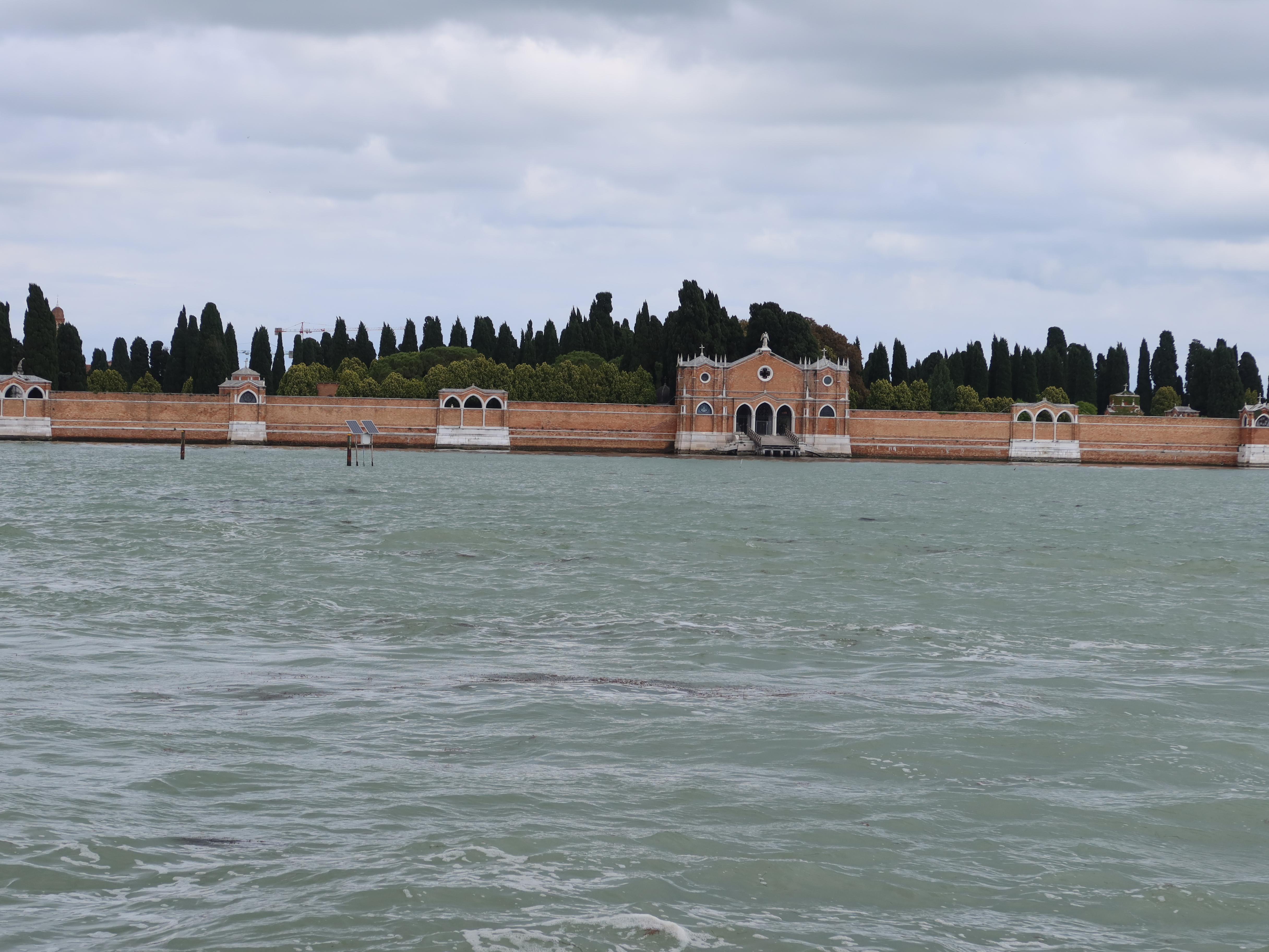 Fortified island structure with arched entrance, brickwork, surrounded by water and trees.