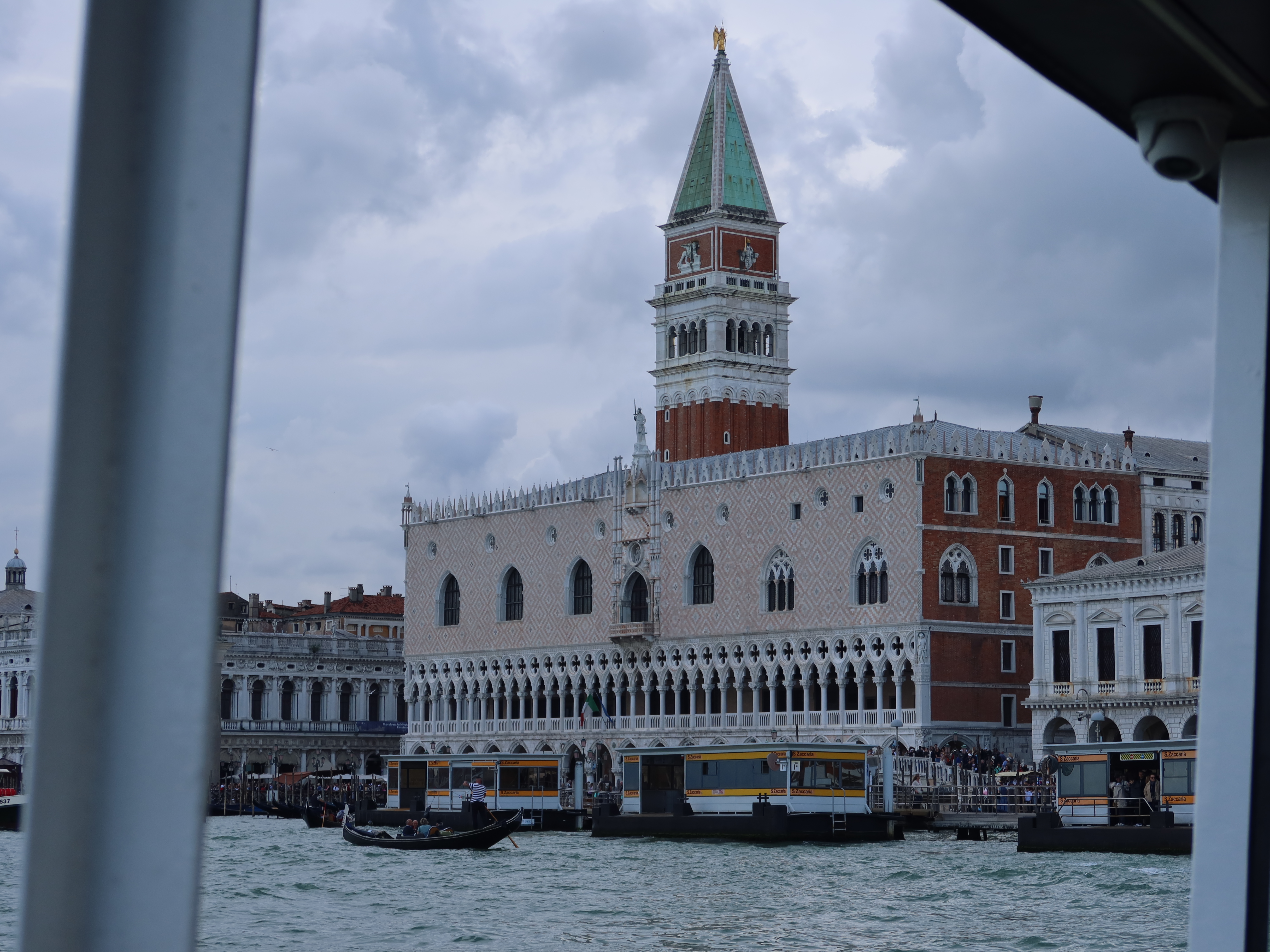 Gothic Building and Canal Scene with Gondola Gothic building and tall bell tower by canal with gondola; overcast sky adds a moody atmosphere.