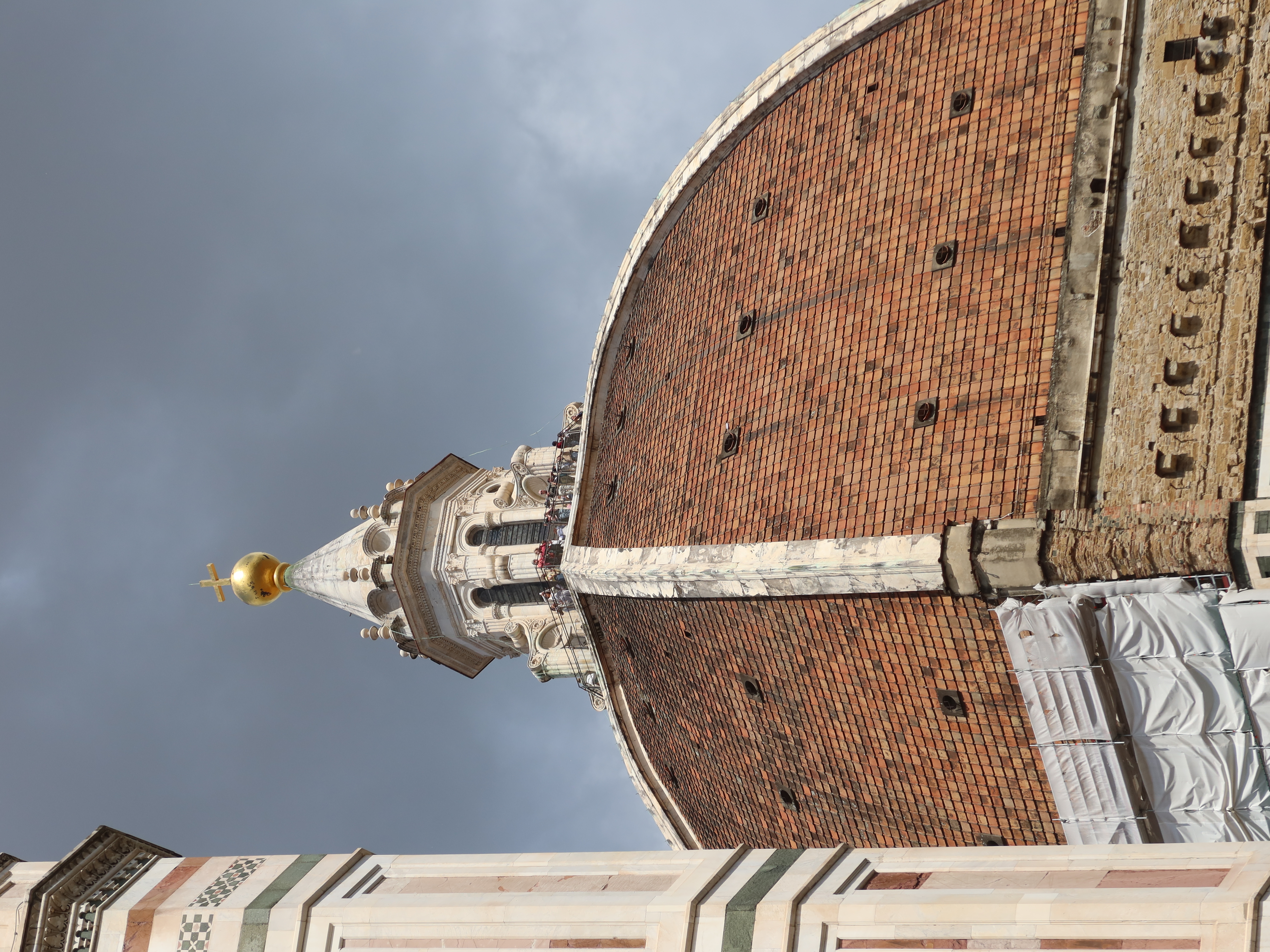 Large dome with red tiles, white structure, golden sphere, cross; historic, under restoration.
