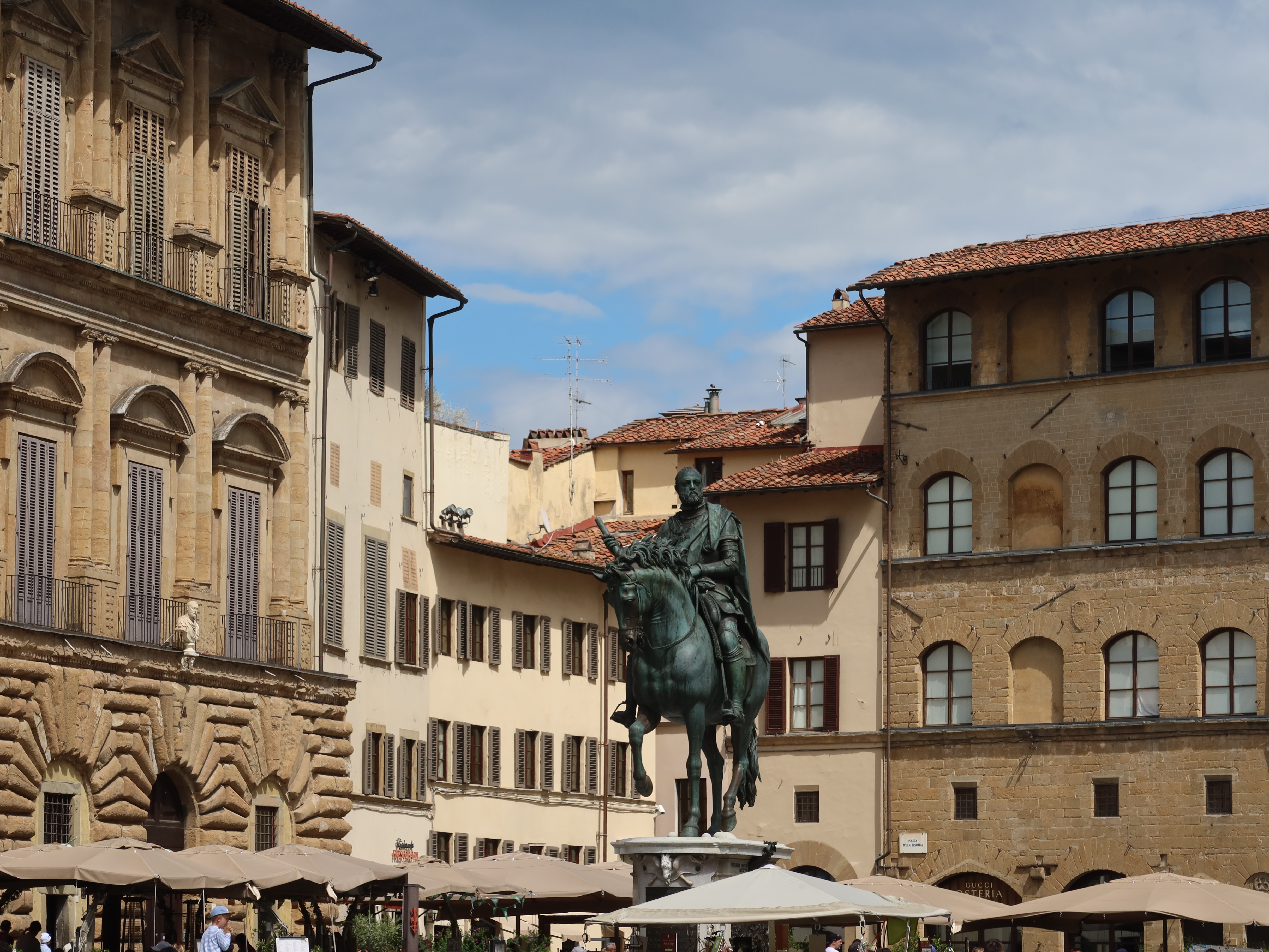 Renaissance Square with Equestrian Statue Historic square with equestrian statue, surrounded by Renaissance buildings and outdoor umbrellas.