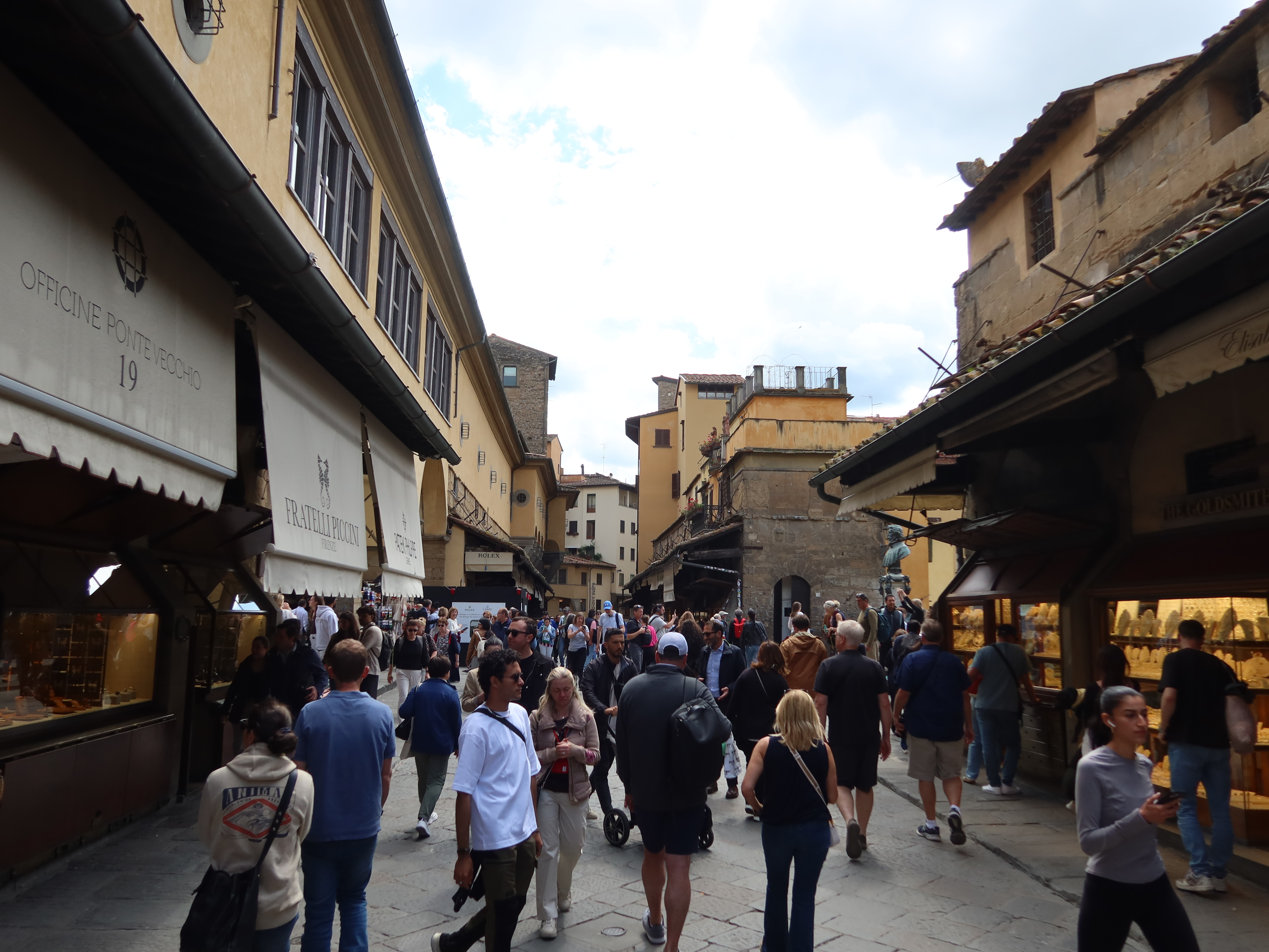 Bustling Ponte Vecchio street in Florence with pedestrians, shops, historic architecture.