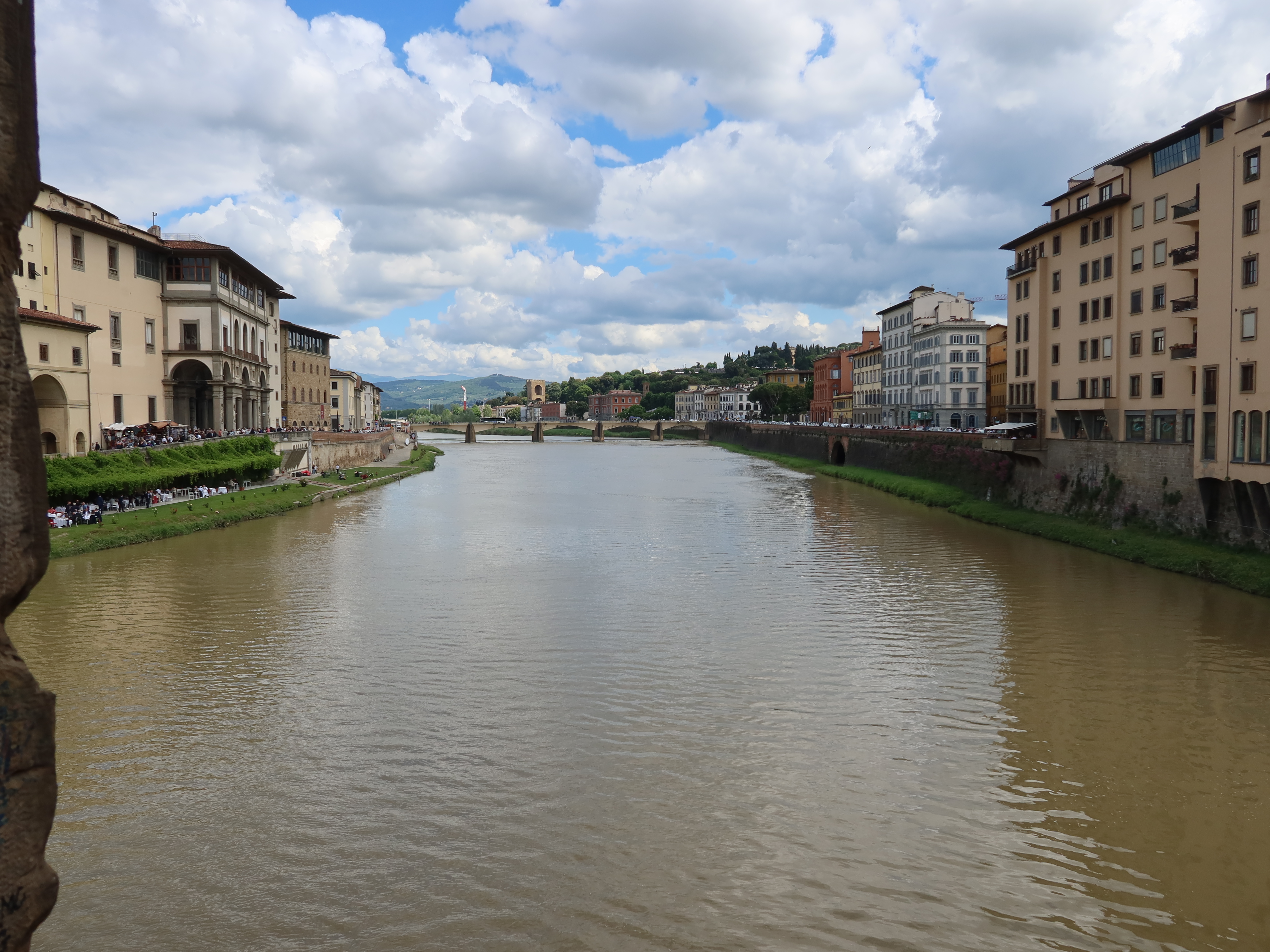 Cityscape with River and Bridge River flowing through city with diverse architecture, bridge, and partly cloudy sky above.