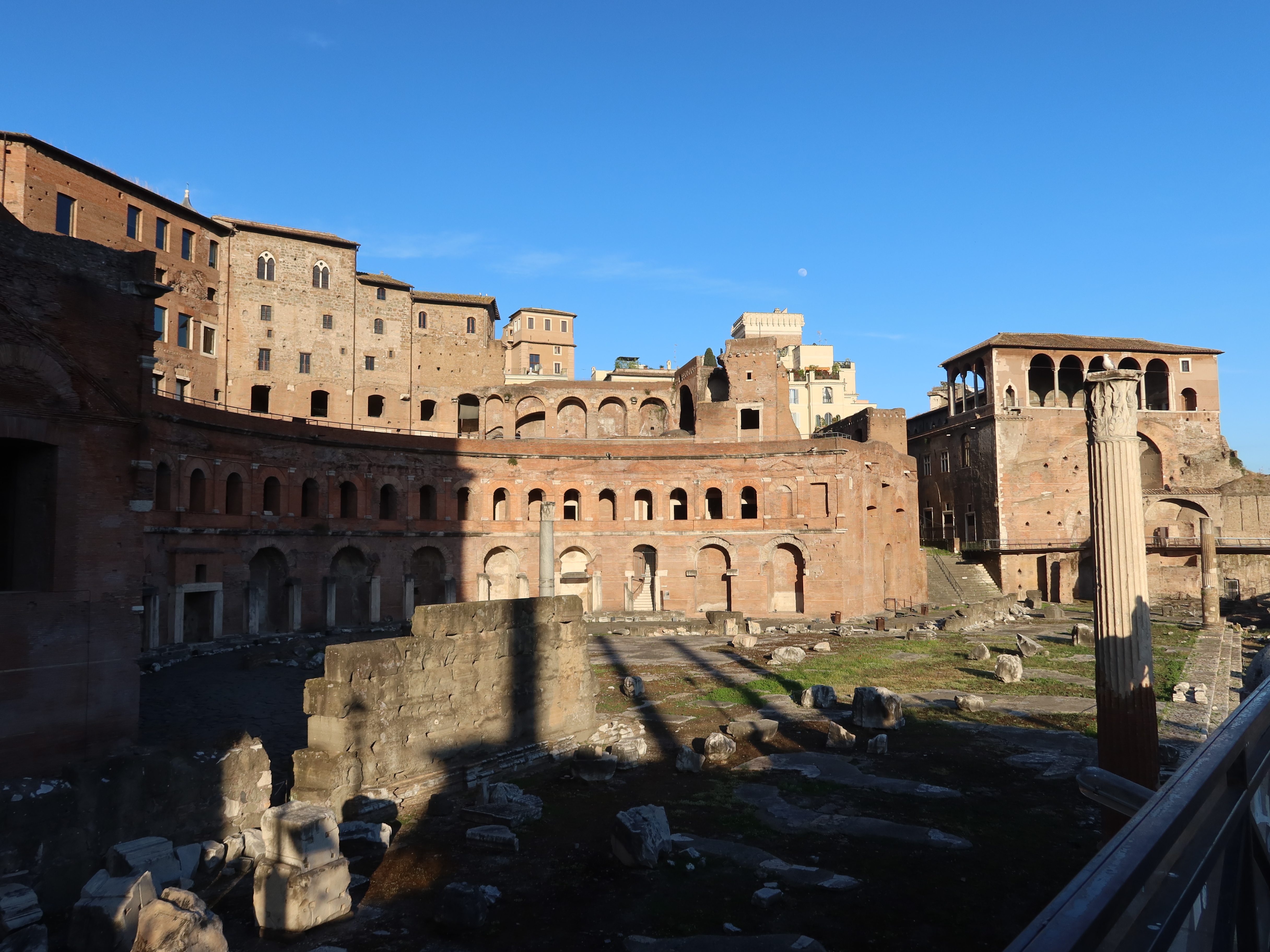 Historic Roman ruins with stone structures, arches, columns, and shadows on a clear day.