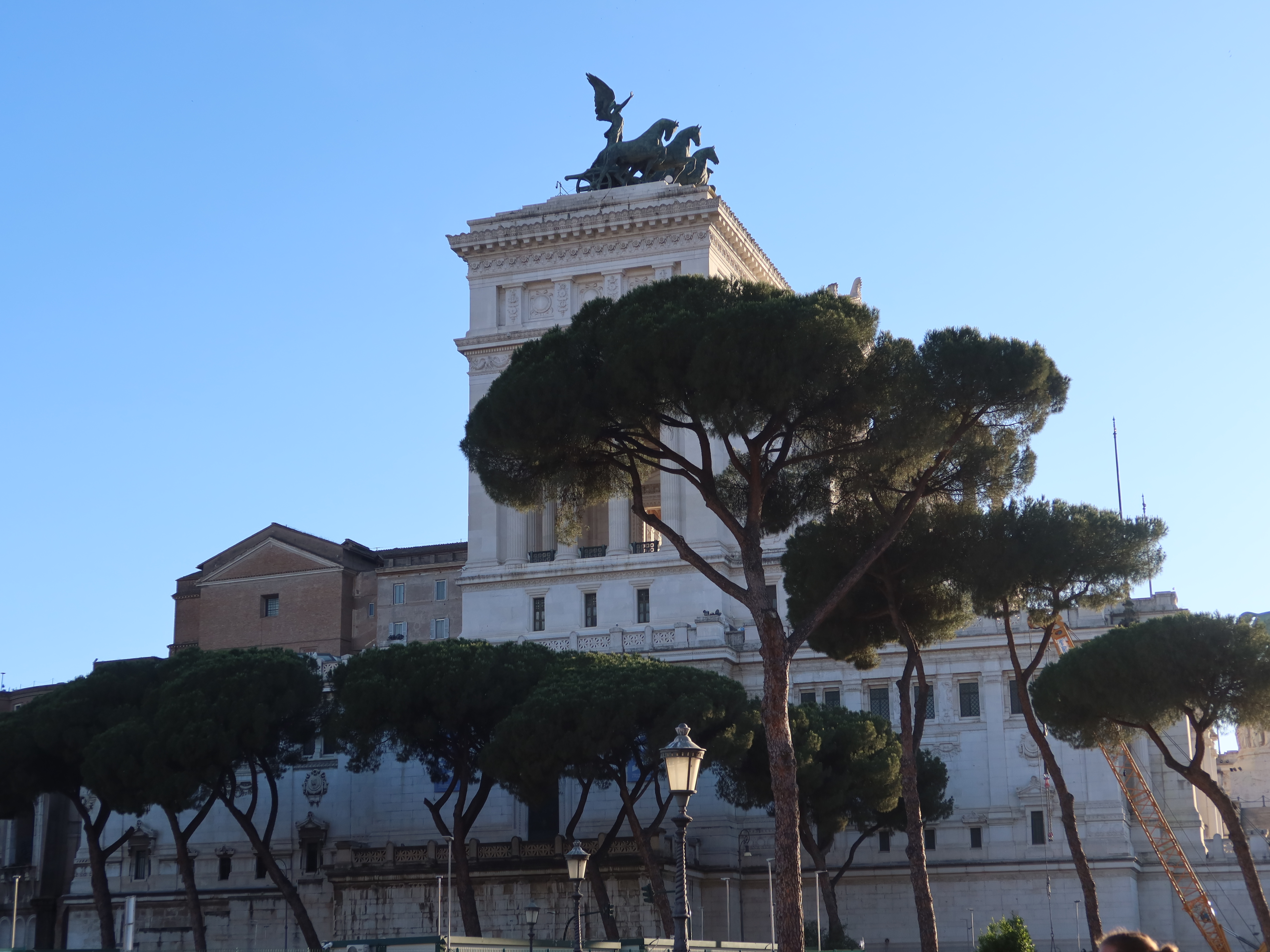Altare della Patria, Rome, with neoclassical architecture, trees, and clear sky in the background.